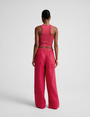 Woman wearing a red ribbed cropped tank and red linen pants against a plain background. 