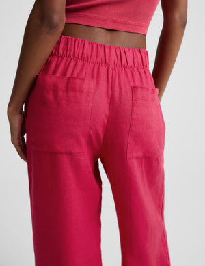 Woman wearing a red ribbed cropped tank and red linen pants against a plain background. 