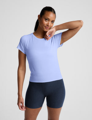 Woman wearing a light blue active short sleeve top and navy blue biker shorts against a plain background. 
