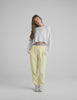 Woman wearing a white long sleeve and yellow sweatpants. 