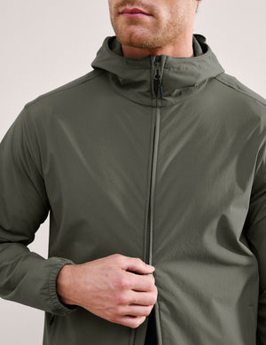 Man wearing a green jacket and shorts on a plain background. 