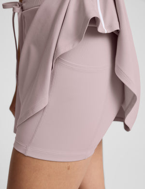 Sport Active Drawcord Mini Skirt in pink; side view showing built-in shorts with a pocket and white piping on the hem.