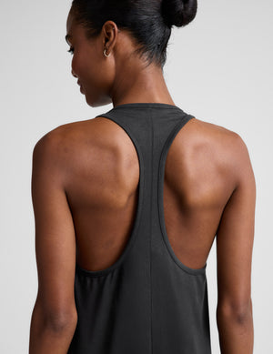 Woman wearing a black sleeveless racerback maxi dress on a light gray background. 
