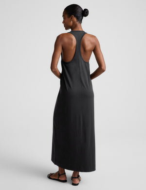 Woman wearing a black sleeveless racerback maxi dress on a light gray background. 