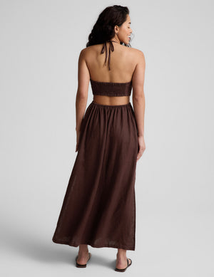 Woman wearing a brown halter neck midi dress on a plain background. 