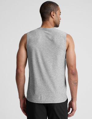 man wearing a gray sleeveless shirt against a plain background. 