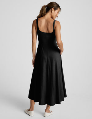 Woman wearing a black sleeveless dress on a white background. 