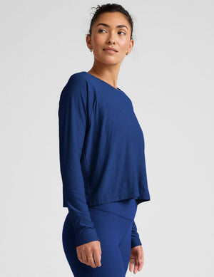 Woman wearing a blue long-sleeve top and leggings against a light background. 