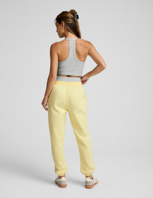 Back view of a woman wearing pale yellow LuxeFleece Sweatpant joggers with an elastic waistband and gathered ankle cuffs.