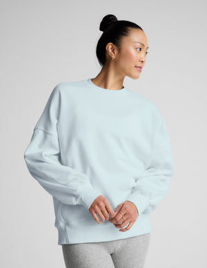 Woman wearing a light blue sweatshirt against a plain background. 