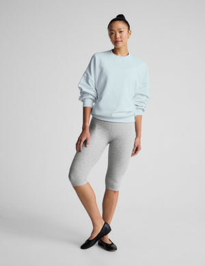 Woman wearing a light blue sweatshirt against a plain background. 