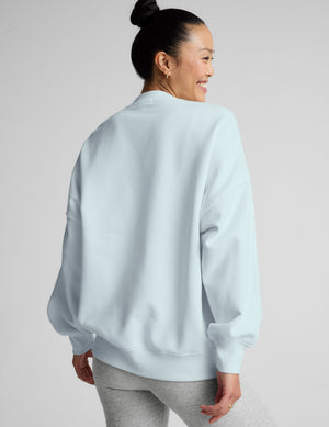 Woman wearing a light blue sweatshirt against a plain background. 