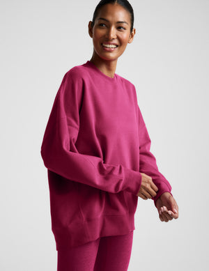 Woman wearing a red crewneck sweatshirt and leggings against a light gray background. 