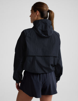 Woman wearing a blue hooded jacket and shorts against a plain background. 