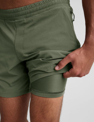 model wearing green men's lined shorts on a plain background. 