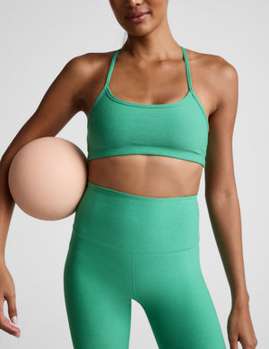 Woman wearing a green bra and green high-waisted midi leggings against a plain background. 
