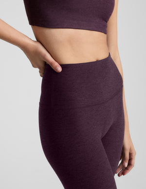 Woman wearing purple leggings on a light gray background. 
