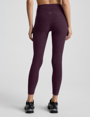 Woman wearing purple leggings on a light gray background. 
