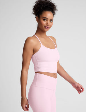 Woman wearing a pink sports bra and leggings on a light gray background