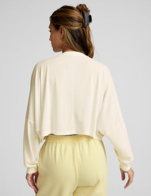 Woman wearing a light-colored outfit with a plain background. 